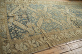 Low angle view of the distressed Kurdish carpet's expansive geometric pattern.