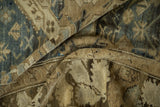 Folded vintage Kurdish carpet highlighting its time-softened, low pile in dusty blue and sandy beige.