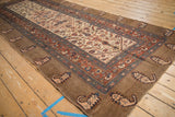 Angled perspective of an antique Serab runner featuring a wide camel border with repeating botehs.