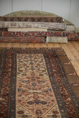 Antique Serab runner styled with a collection of rolled vintage and antique rugs in a studio setting.