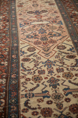 Angled view along an antique Serab runner showing the detailed camel border and dusty rose lattice field.