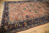 Angled view of a distressed Lilihan carpet highlighting the wide navy border and copper floral field.