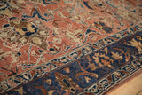 Low angle detail of a distressed Lilihan carpet's navy border and copper-toned floral field.