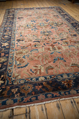 Angled perspective on a distressed Lilihan carpet's copper floral field and wide navy border.