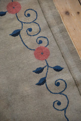 Antique Art Deco rug's scrolling cobalt vine and blush palmette detail on ivory ground.