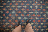 Overhead detail of a distressed Kurdish carpet's boteh and floral trellis pattern showing its low-pile texture.