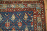 Corner view of an antique Kurdish carpet's meandering blossom border and its red diamond trellis field.