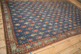 Perspective view of a distressed Kurdish carpet showing its repeating trellis pattern and floral motifs.