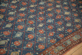 Close-up of a distressed Kurdish carpet's blue field, showing red trellis panels with boteh and floral motifs.