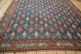 Angled view across the distressed surface of an antique Kurdish carpet's geometric trellis field.