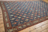Detail of the meandering blossom border and diamond-panel field on an antique Kurdish carpet.