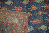 Folded corner of an antique Kurdish carpet showing the worn, hand-knotted pile and detailed border.