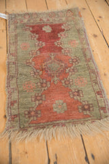 Antique Oushak rug mat with visible tatter and even wear, shown from a perspective angle.