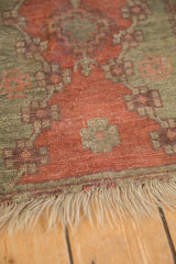 Even wear across the low, hand-knotted pile of an antique Oushak mat, with its fringe visible.