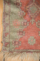 Detail of an antique Oushak mat showing even wear to knot heads and tattered fringe.