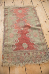 Angled view of an antique Oushak mat, highlighting the even wear and tattered perimeter of the piece.
