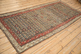 Angled perspective of an antique Qashqai runner showing its allover floral design and madder red border.