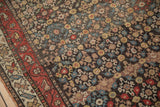 Detailed knot heads of an antique Qashqai rug showing repeating floral designs against a charcoal field.