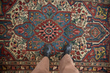 A person's view of the detailed starburst medallion on a vintage Persian Baktiari rug.
