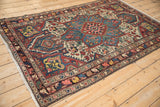 Angled view of a hand-knotted Bakhtiari rug showing its central starburst medallion and floral field.