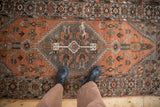 Distressed vintage Hamadan runner with geometric patterns in soft rust and grey tones.