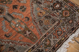 Distressed vintage Hamadan runner's corner, with pale chestnut, silver patterns, and ivory fringe.