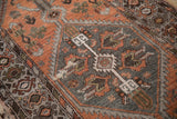Distressed Hamadan runner's hexagonal medallion with rust floral designs and ivory tiered finial.