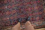 Overhead view of detailed vined medallions and serrated leaf motifs on an antique Malayer rug.