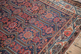 Angled detail of a fine Malayer carpet's geometric medallions and meandering vine border.