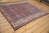 Angled view of an antique Malayer carpet, showing its full geometric pattern and rich color palette.
