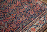 Angled detail of an antique Malayer carpet showing its cobalt blue field and ivory vine border.