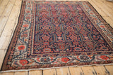 Angled view of an antique Malayer carpet's scrolling medallions in indigo and madder red.