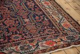 Antique Persian Malayer carpet corner showing the cobalt blue field and meandering vine border.