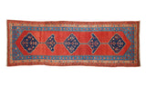 Antique Persian Bakshaish runner with a column of interconnected blue medallions on a madder red field.