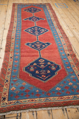 A long perspective of the antique Bakshaish runner's interconnected medallions on a red field.