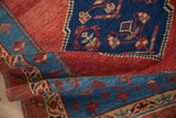 Textured wool pile of a folded antique Bakshaish rug in rich madder red and sapphire blue.