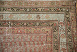 Distressed antique Malayer carpet corner, faded ruby red and slate blue meandering vine borders.