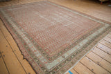 Distressed Persian Malayer carpet showing faded red boteh field and ornate vine borders.