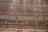 Storied borders of antique Malayer rug: faded ruby red, slate blue vine patterns, fringe.