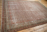 Corner detail of the antique distressed Malayer carpet, showcasing meandering vine borders and time-softened tones.