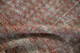 Distressed Malayer carpet pile with faded ruby red, slate grey, and visible foundation.