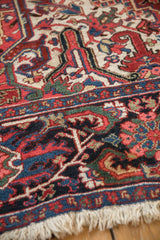 Vintage Ahar carpet detail: scrolled leaves, intricate vines, navy border, and cream fringe.