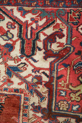 Hand-knotted Ahar carpet detail: scrolled leaves and vines in brick red, beige, and blue.
