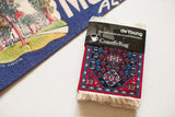 Packaged Persian Qashqai CoasterRug with red and blue intricate medallion pattern and white fringe.