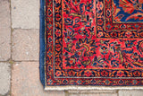 Intricate corner detail of antique Kashan rug: rich red field, royal blue border, white knots.