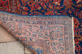 Antique Persian Kashan rug corner, displaying royal blue pile, white knots, and faded coral pink foundation.