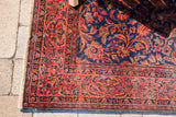 Antique Kashan rug corner with intricate royal blue floral motifs and visible white knots.