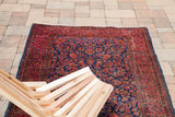 Antique Persian Kashan rug with intricate royal blue and rich red floral motifs, featuring white knots.