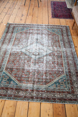 Distressed vintage Malayer rug's faded character, showing silver, teal, and blanched red motifs.