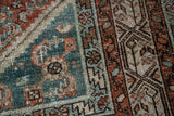 Malayer rug close-up, revealing distressed texture and muted teal, slate blue, terracotta patterns.